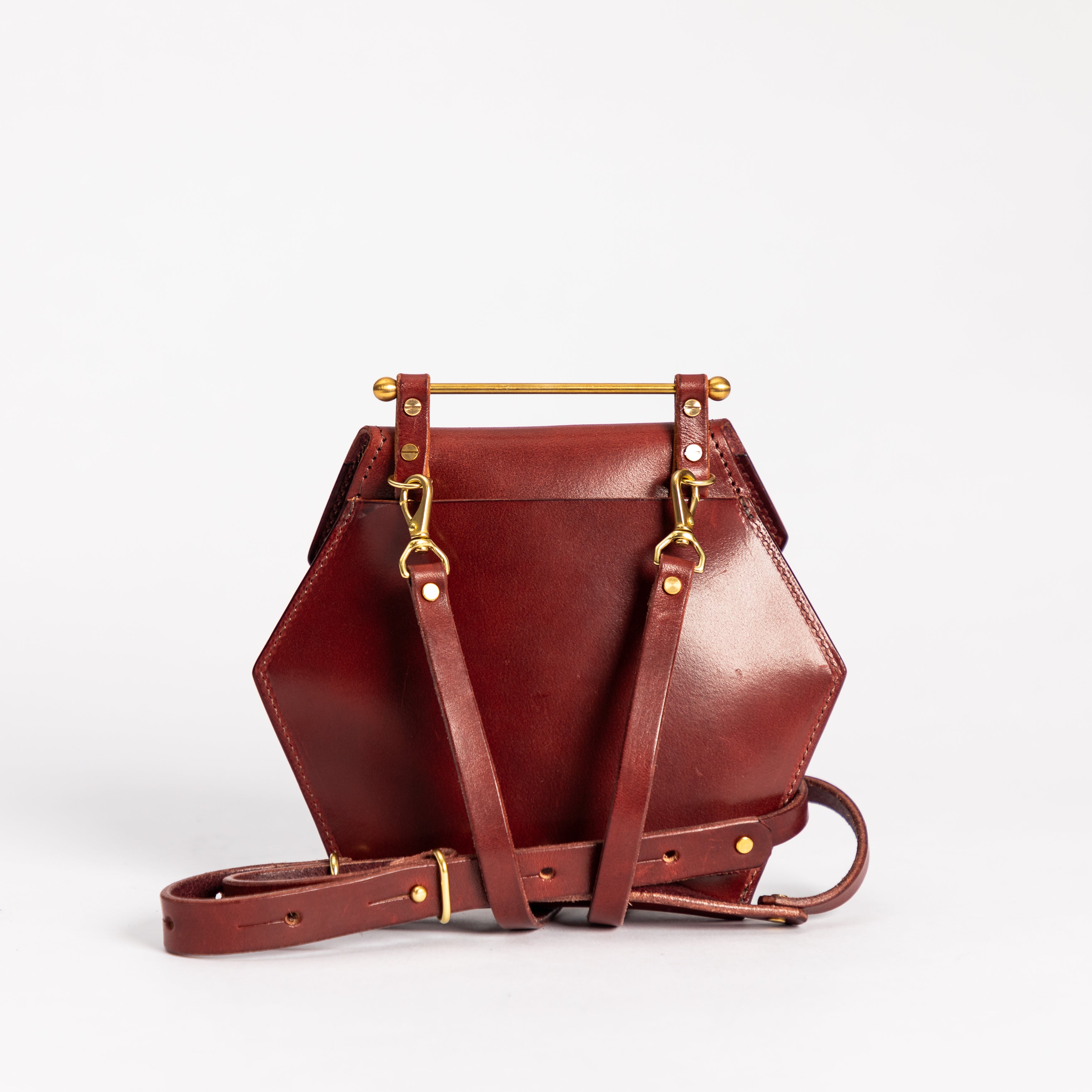 Oxblood honeycomb-shaped small crossbody bag with full grain leather and removable strap on white background