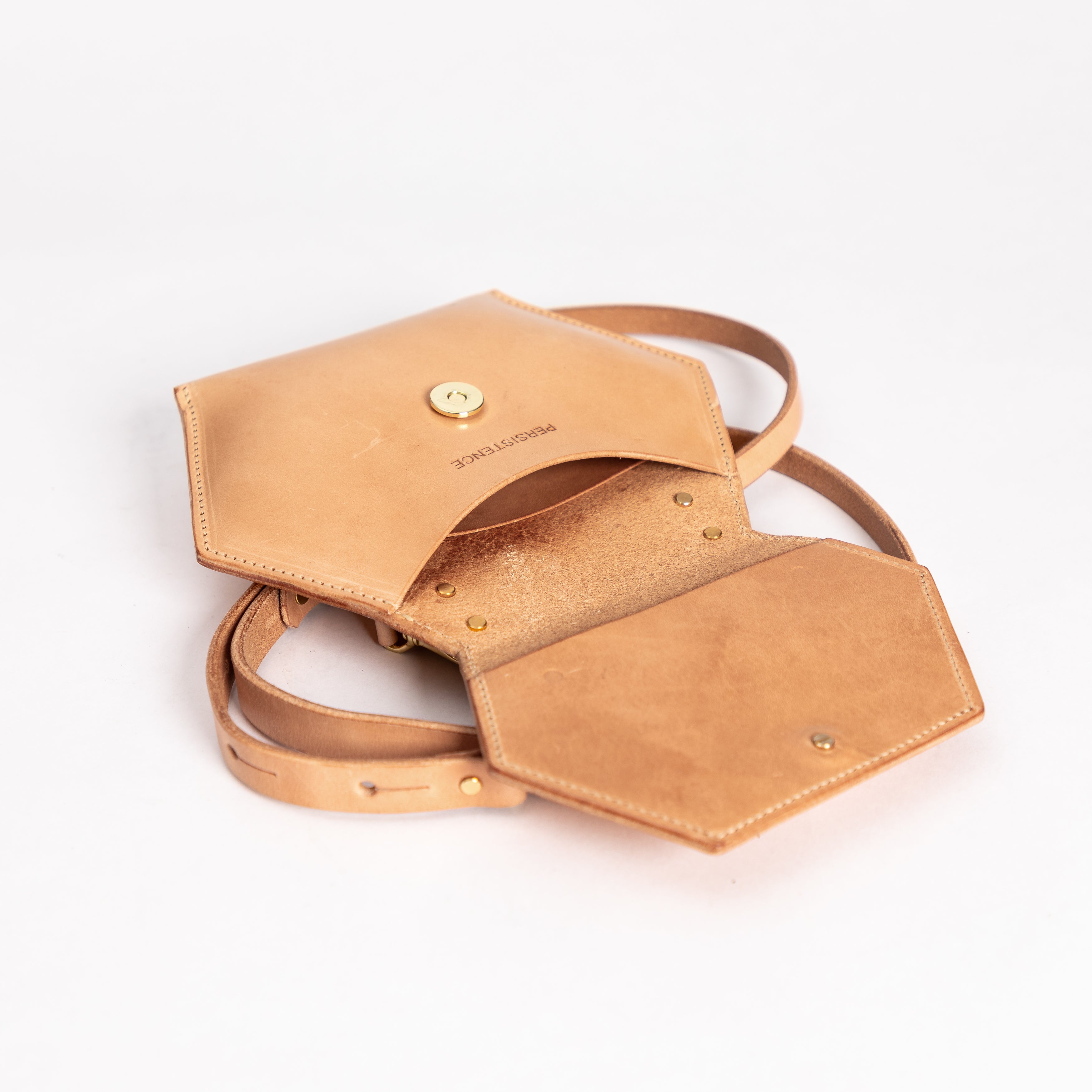 Small honeycomb shaped tan leather crossbody bag with inside pocket and removable strap on white background