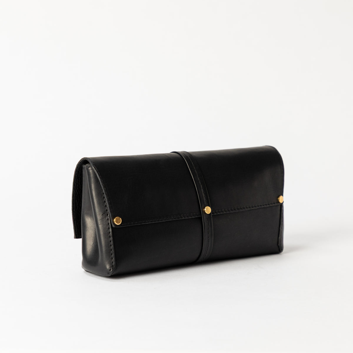 Black Transpose Bag in smooth vegetable-tanned leather styled as a clutch with wraparound strap and solid brass rivets