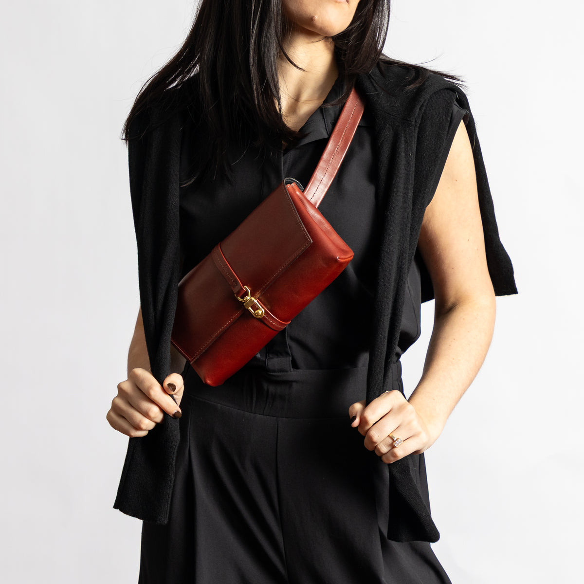 Sangria burgundy Transpose Bag worn as a crossbody sling over a black outfit with full-grain vegetable-tanned leather and brass clasp