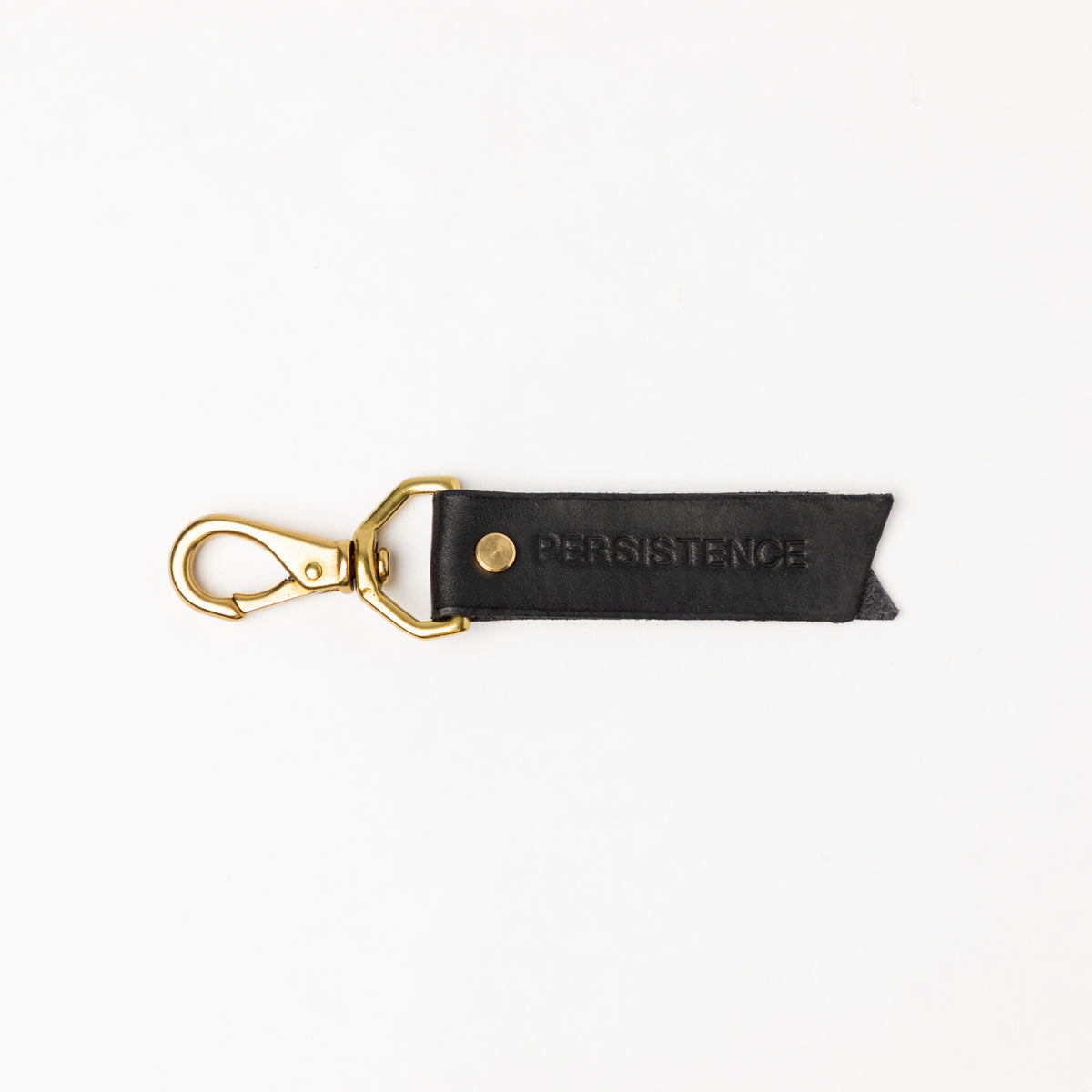 Black full-grain leather keychain with brass hardware and debossed PERSISTENCE text, minimalist small accessory
