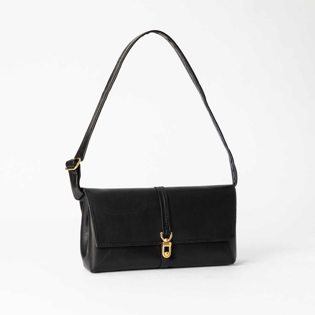 Black Transpose Bag in vegetable tanned leather with a flap front adjustable shoulder strap and polished solid brass hardware