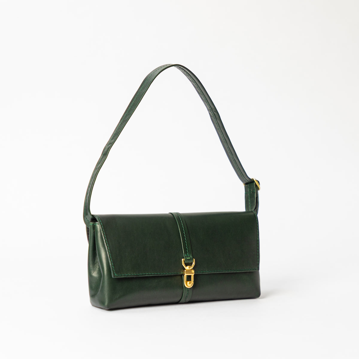 Dark green leather shoulder bag with a slim strap structured flap and brass clasp against a white background